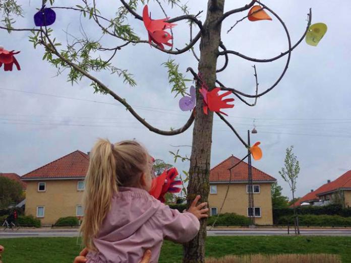 Barn hænger pynt på træ