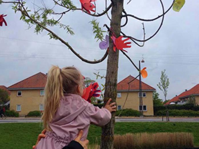Barn hænger pynt på et træ