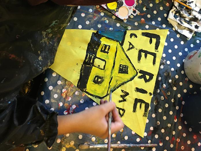 Barn maler skilt hvor der står FerieCamp