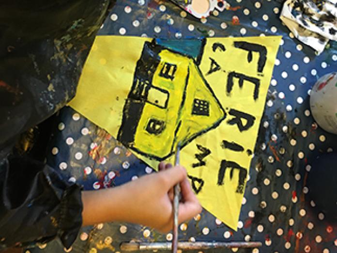 Barn maler skilt, hvor der står FerieCamp