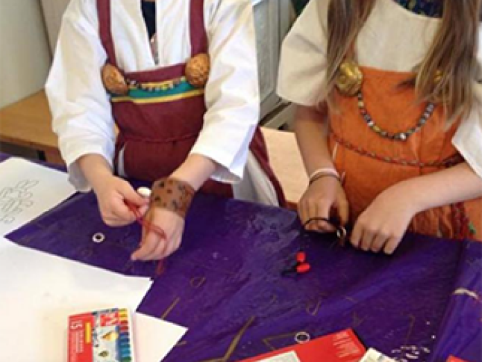 Børn iklædt vikingetøj laver armbånd af læder