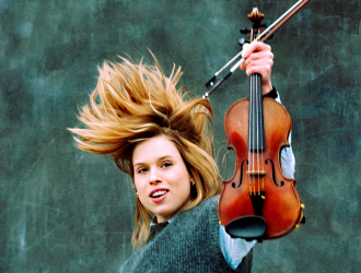 Violinist Emma Elmøe med vind i håret, som holder sin violin